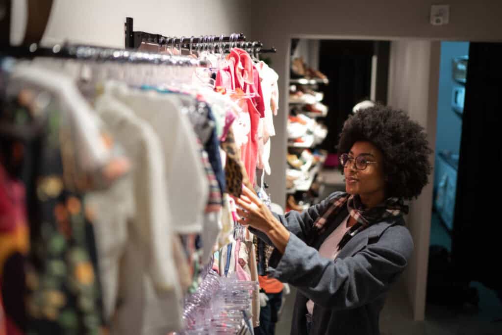 Student organizing thrifted clothing items for resale on Depop or Poshmark